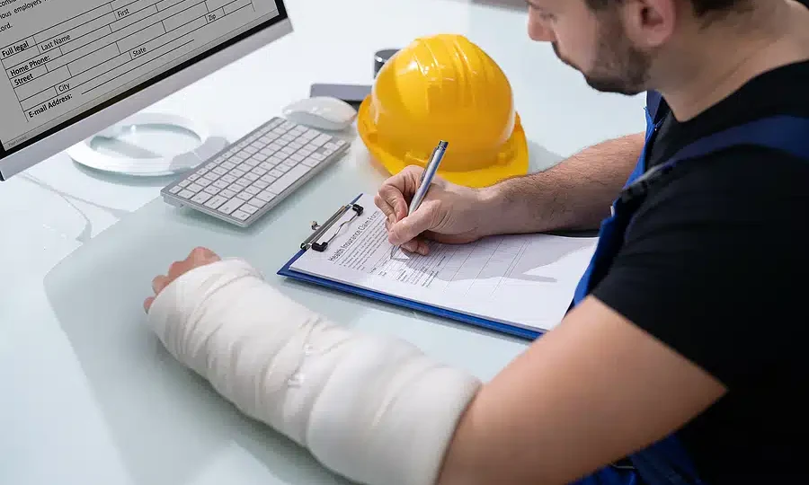 Trabajador con el brazo vendado llenando documentos de seguro