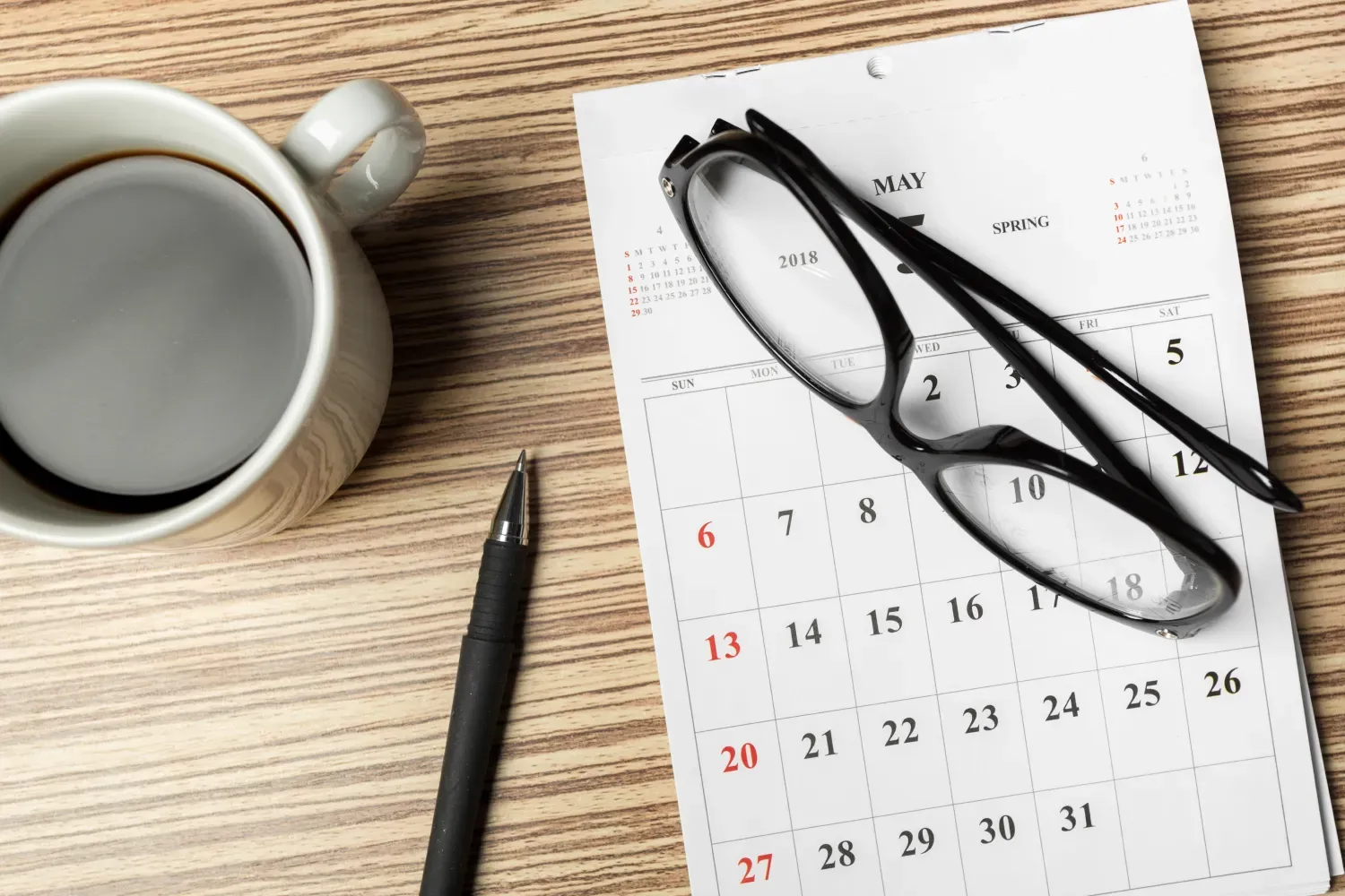 Calendario y reloj sobre un escritorio de madera.
