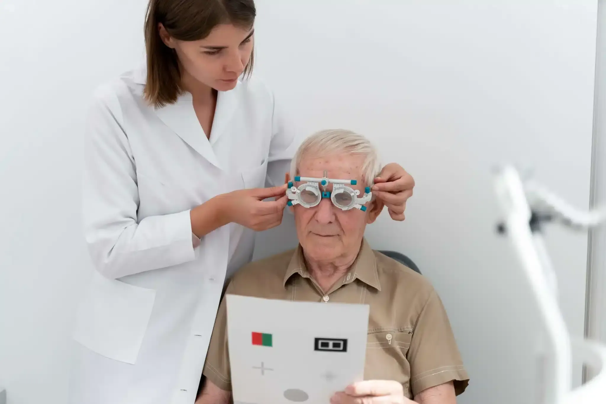 Optometrista ajustando anteojos de prueba a un hombre mayor durante un examen de la vista.