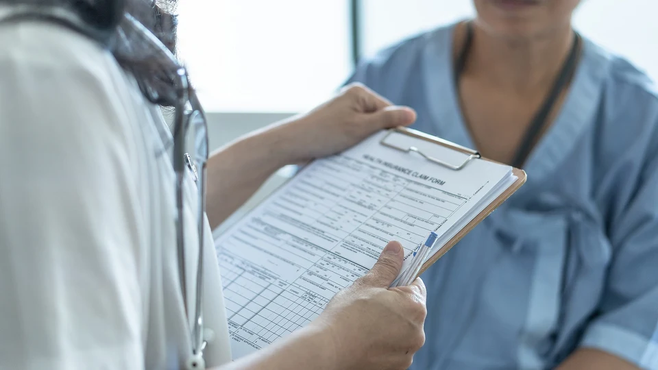Médico revisando un formulario de reclamación de seguro médico con un paciente