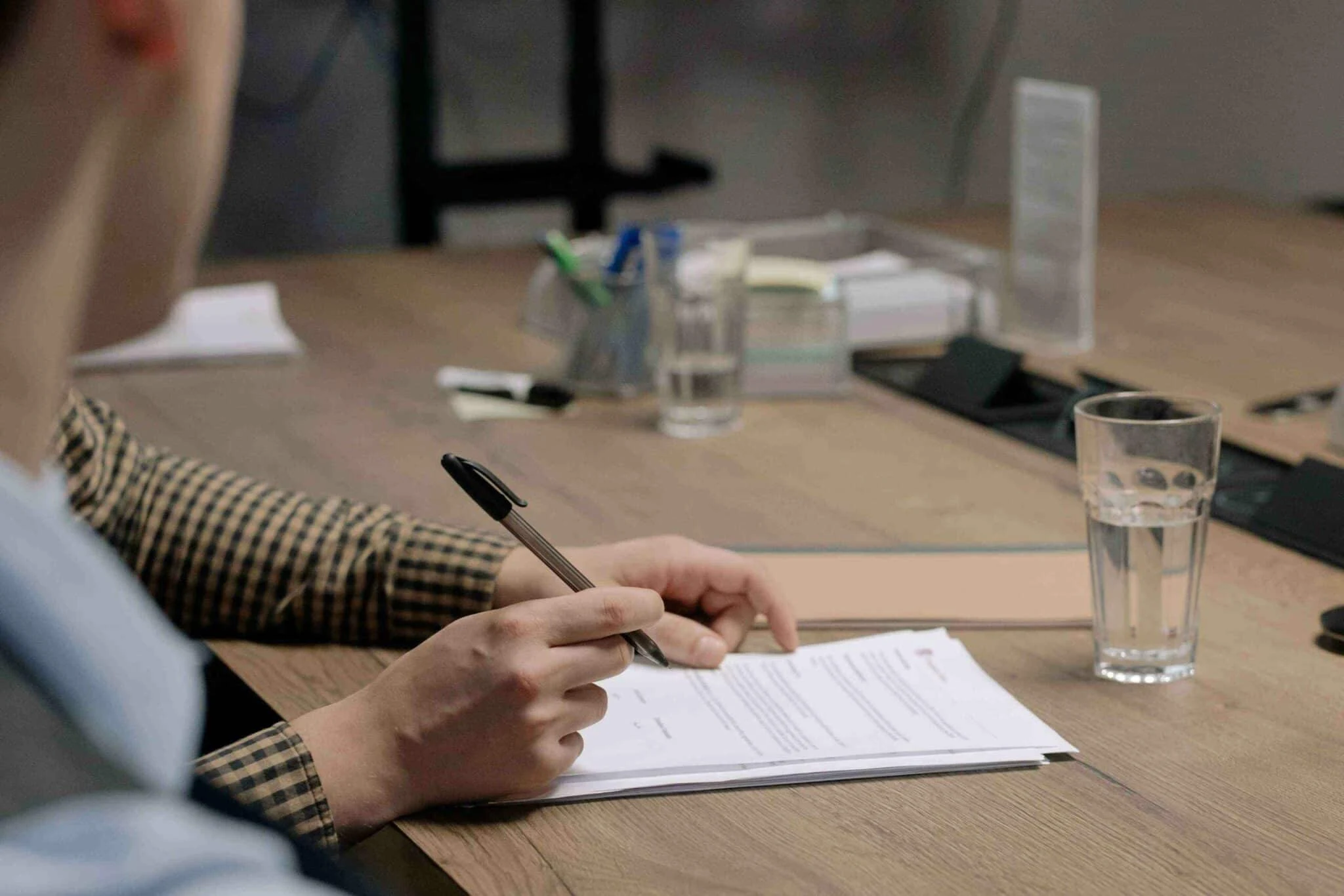 Persona firmando documentos al otro lado de una mesa