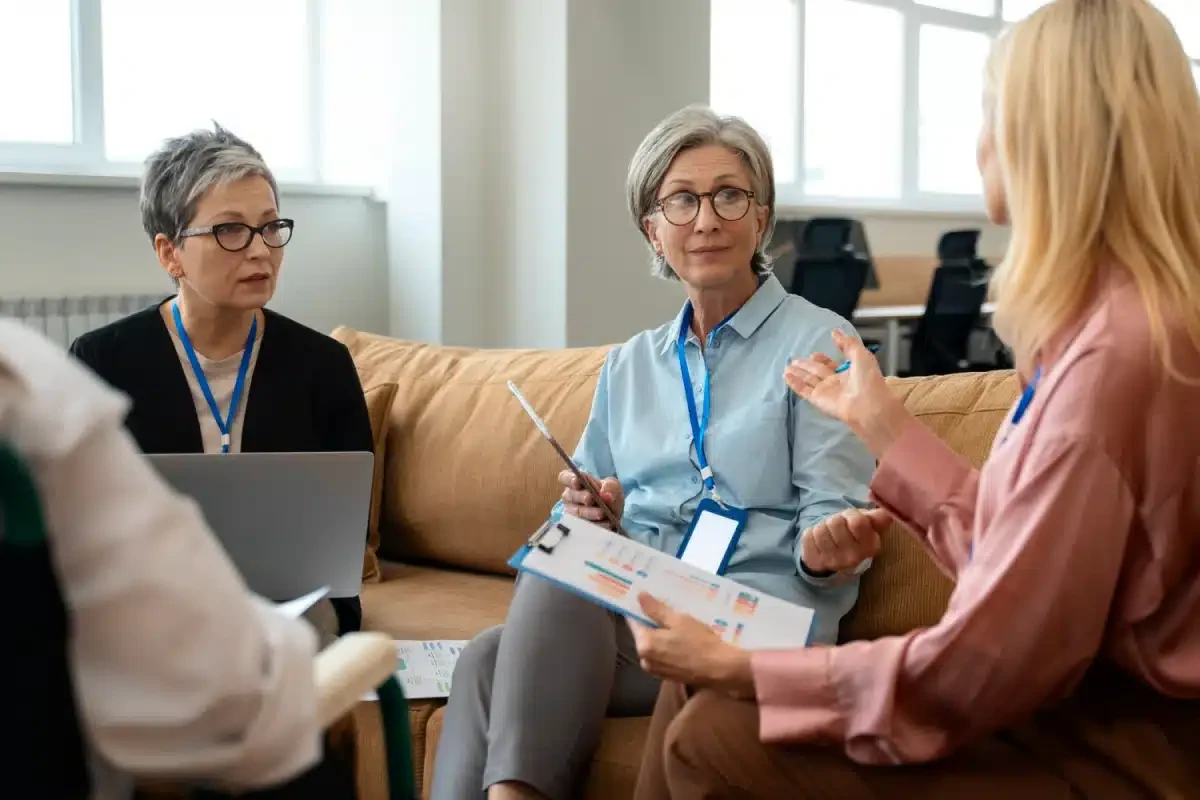 Tres mujeres hablando sobre beneficios para empleados en una reunión de trabajo